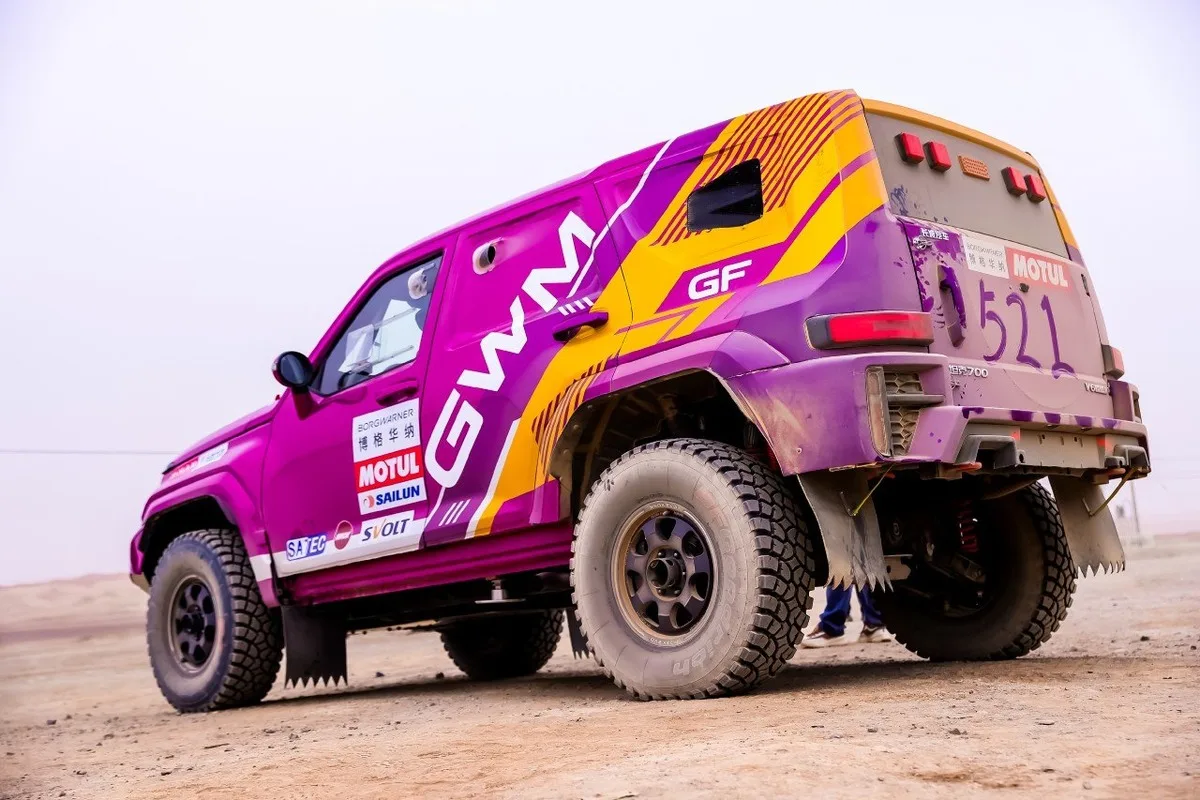 Rear three-quarter view of a magenta GWM TANK rally SUV with desert competition livery.