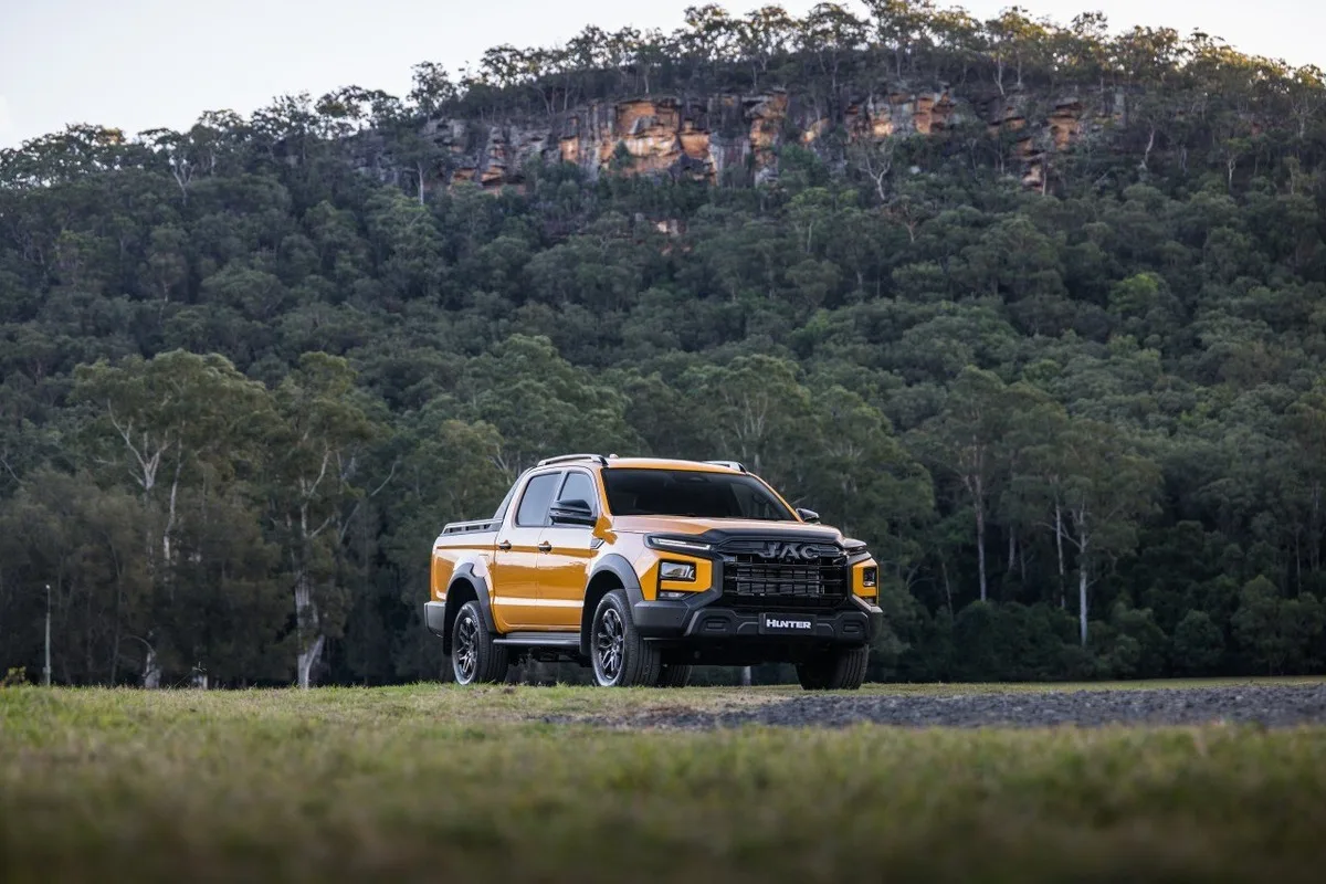 Yellow JAC Hunter PHEV ute parked against a forested hillside.