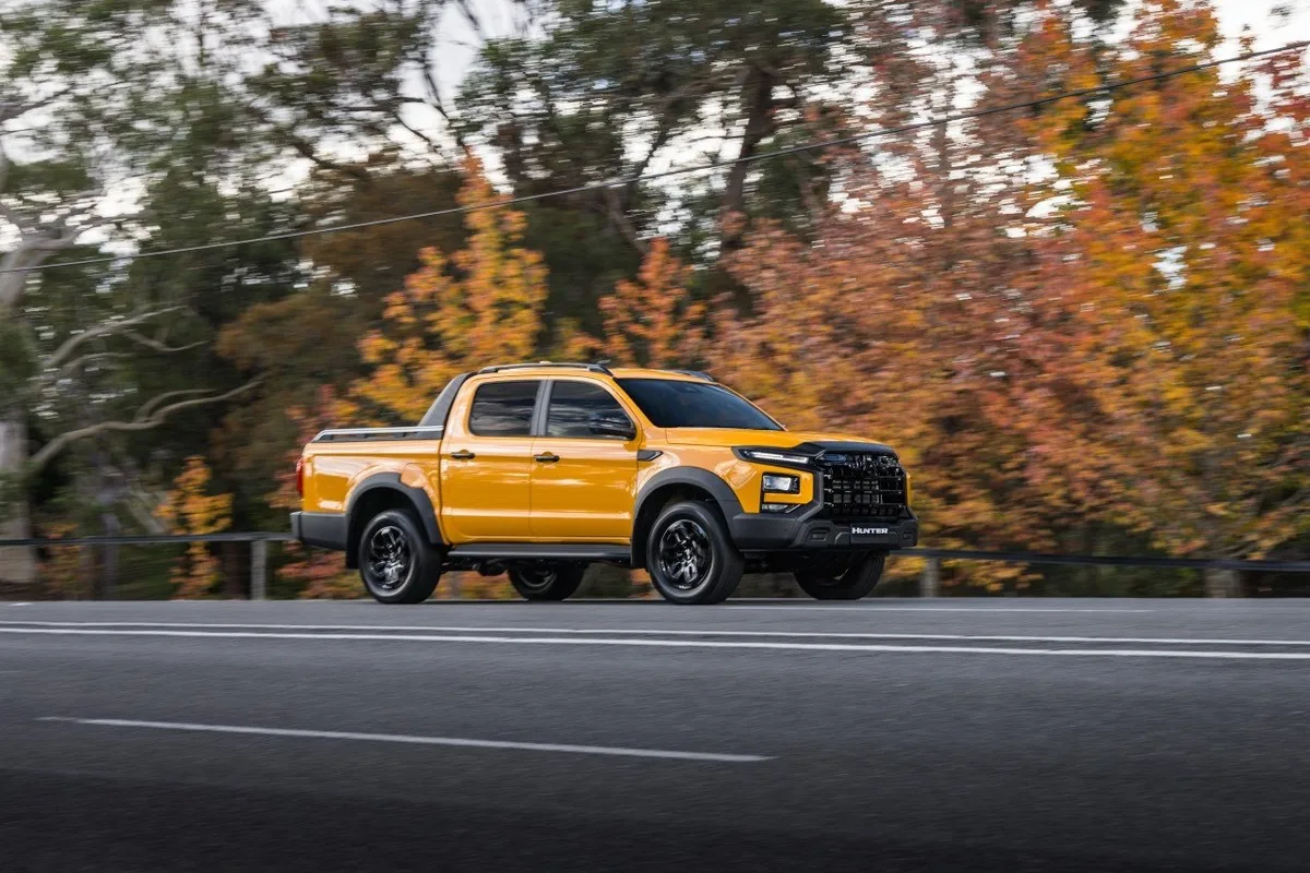 Yellow JAC Hunter PHEV ute driving on a sealed road.