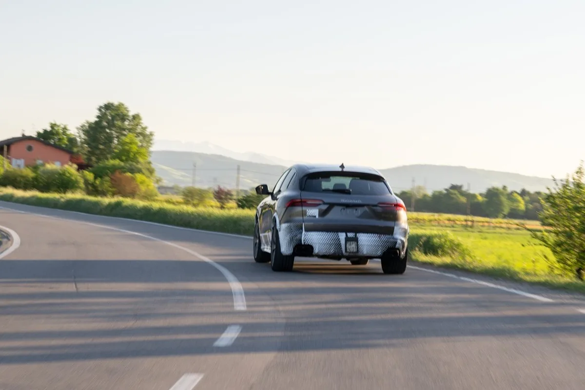 Rear view of a camouflaged Maserati Grecale prototype on a country road