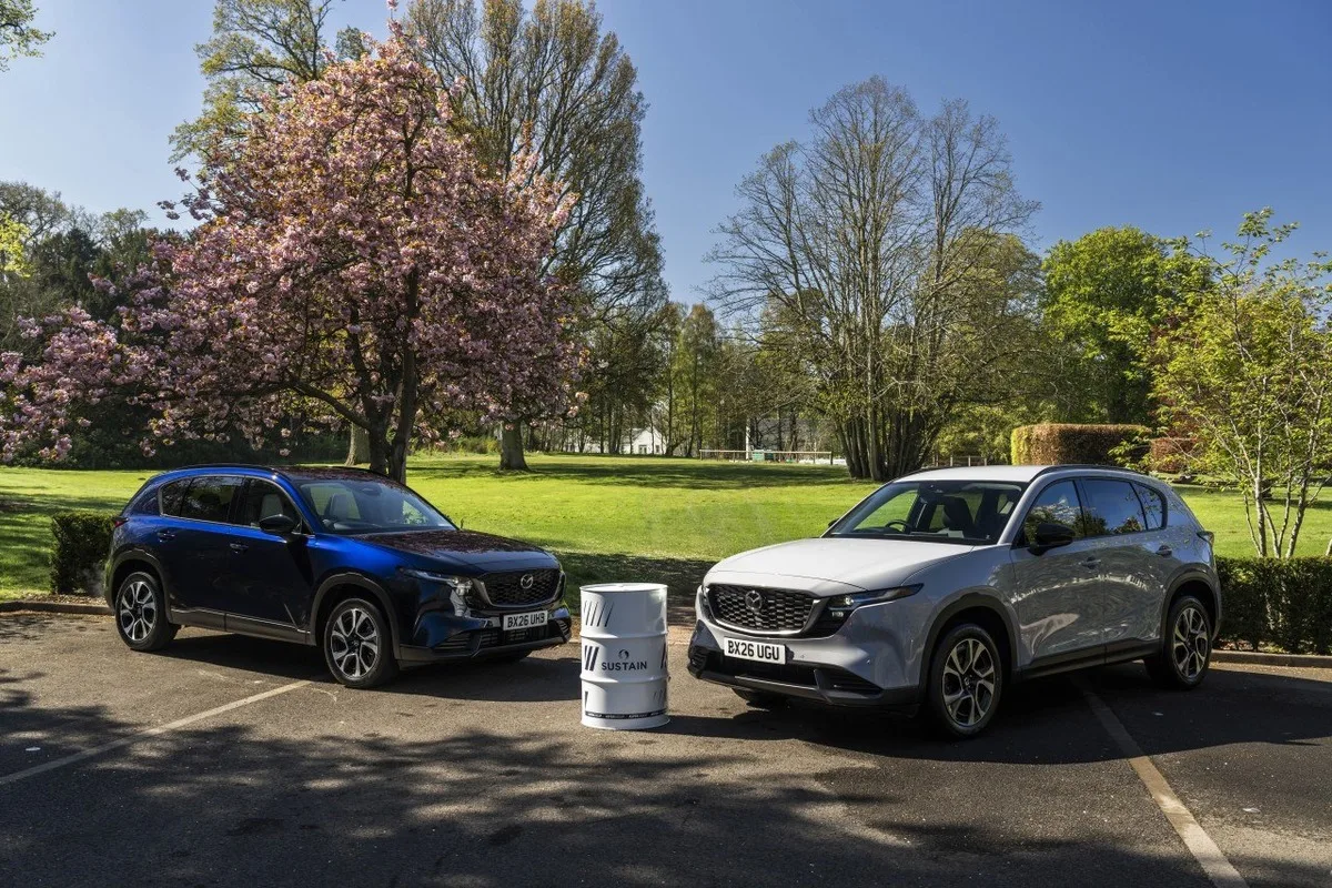 Two Mazda CX-5 SUVs parked beside a SUSTAIN biofuel drum at the UK launch