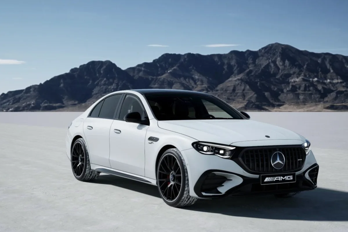 White Mercedes-Benz E 300 AMG Night Edition front three-quarter view on an open test surface.