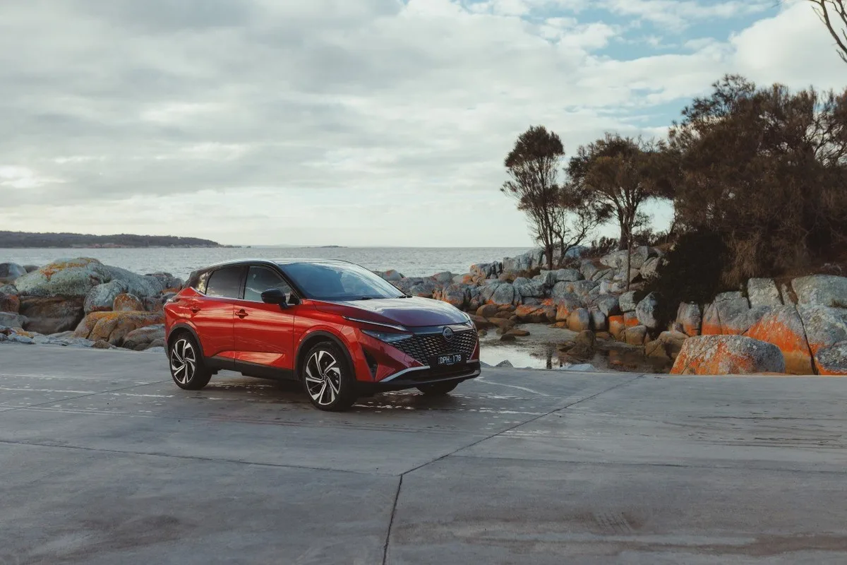 Red Nissan Qashqai e-POWER parked on a rocky Tasmanian coastline.