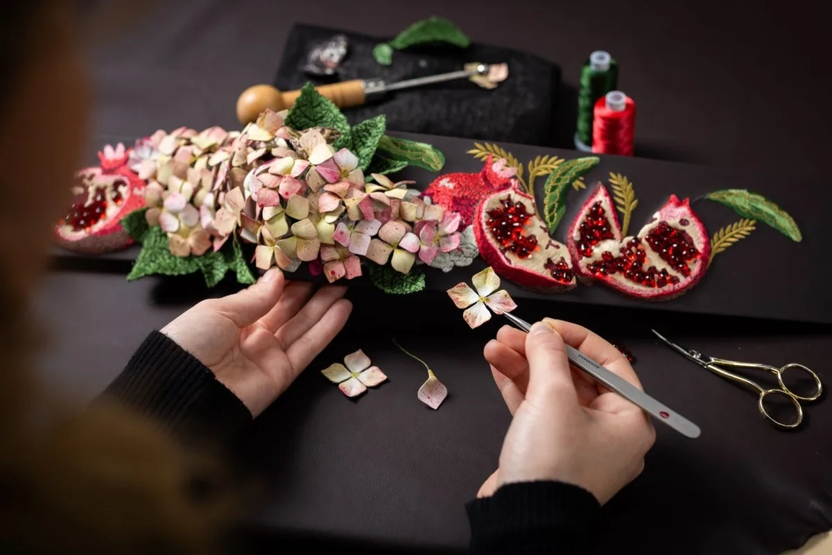 Rolls-Royce Bespoke artisan placing a floral detail on pomegranate and hydrangea-inspired beadwork.