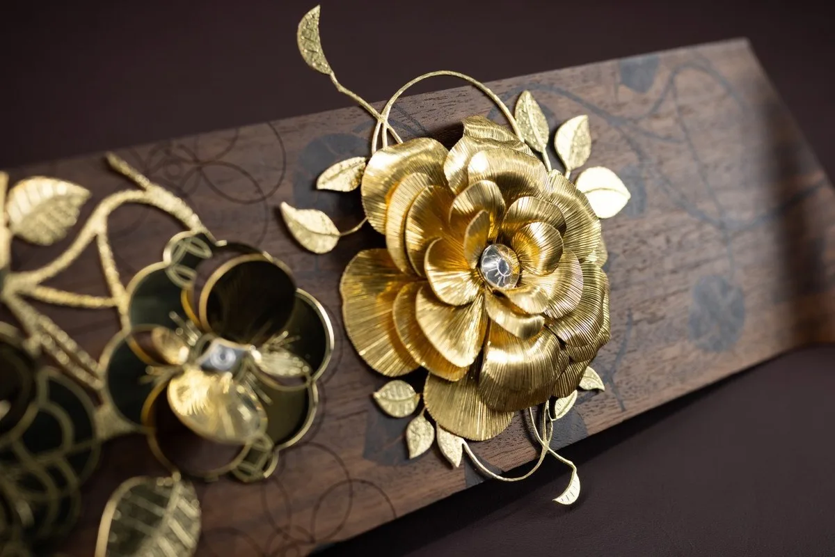 Gold floral Rolls-Royce Bespoke ornament mounted on a patterned wooden panel.