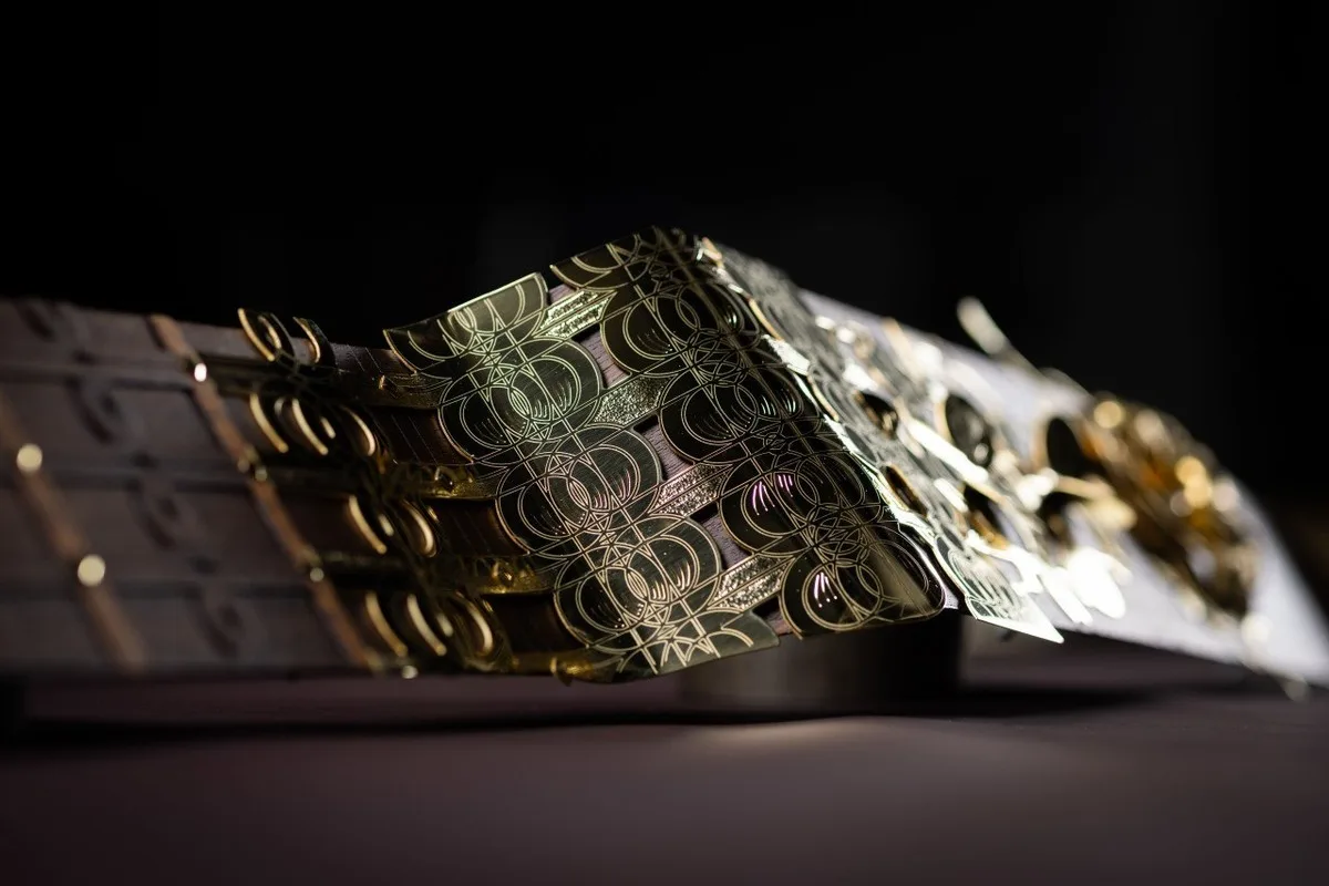 Close-up of polished Rolls-Royce Bespoke gold geometric inlay on a dark surface.