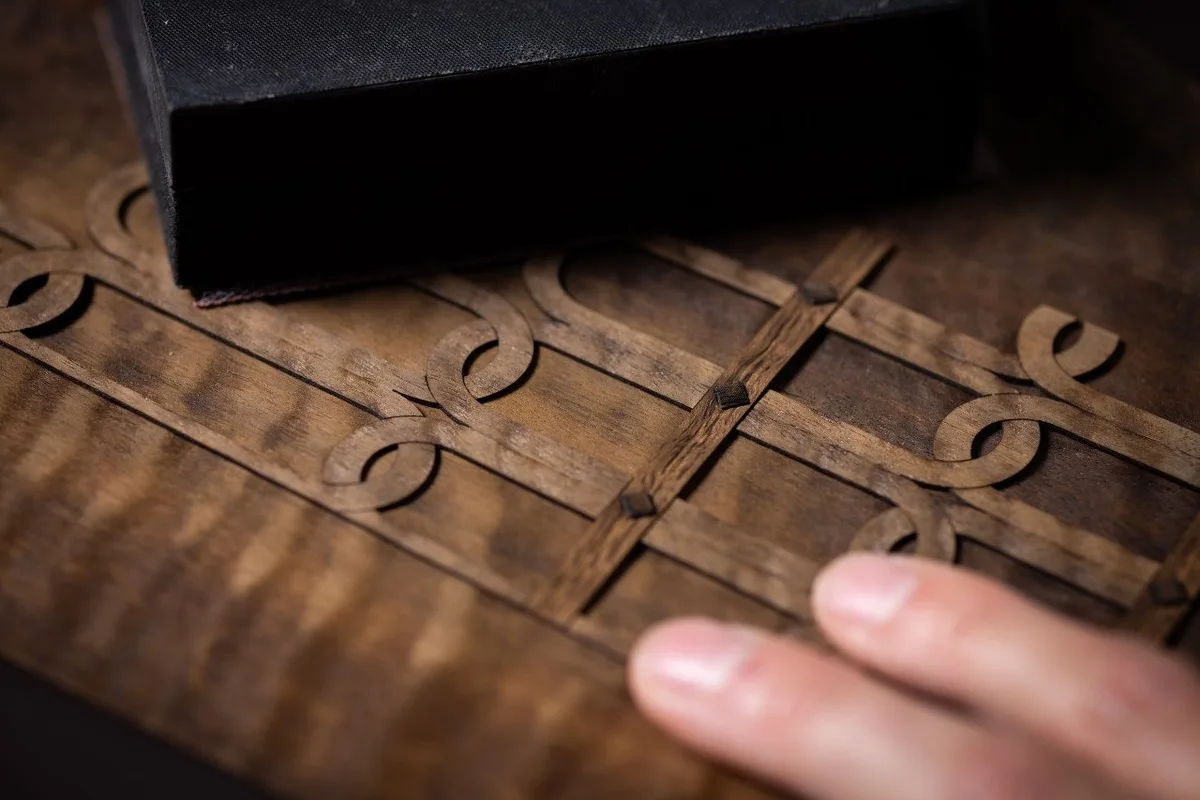Close-up of a Rolls-Royce Bespoke decorative wooden marquetry panel with geometric scrollwork.