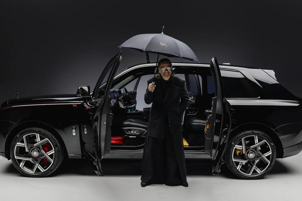 Cyril Kongo standing with a black Rolls-Royce Black Badge Cullinan and umbrella in studio.