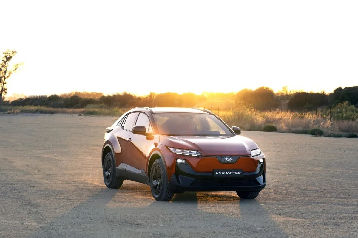 Orange Subaru Uncharted parked on a dusty open landscape at sunset.