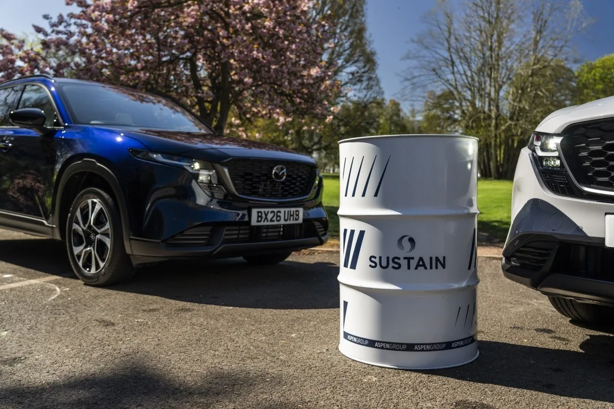 SUSTAIN 100 biofuel drum positioned between Mazda CX-5 launch cars in a sunny park setting