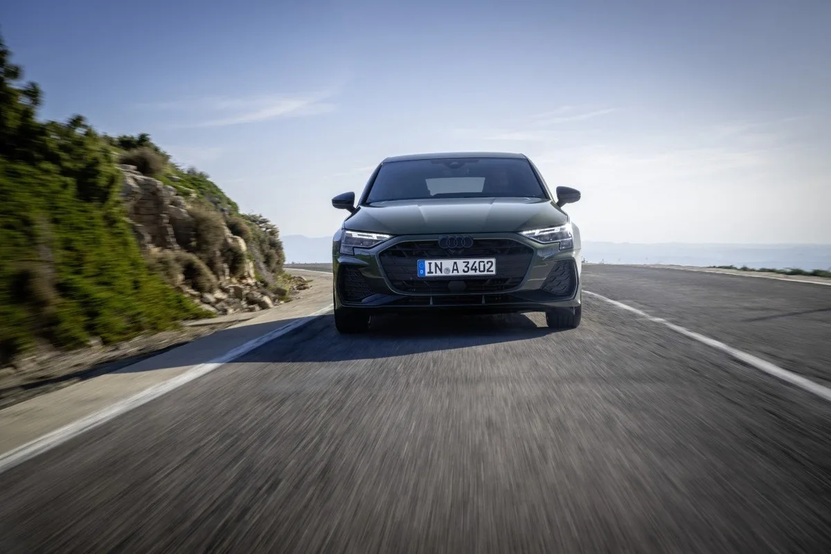 Green 2026 Audi A3 driving toward the camera on a coastal road.