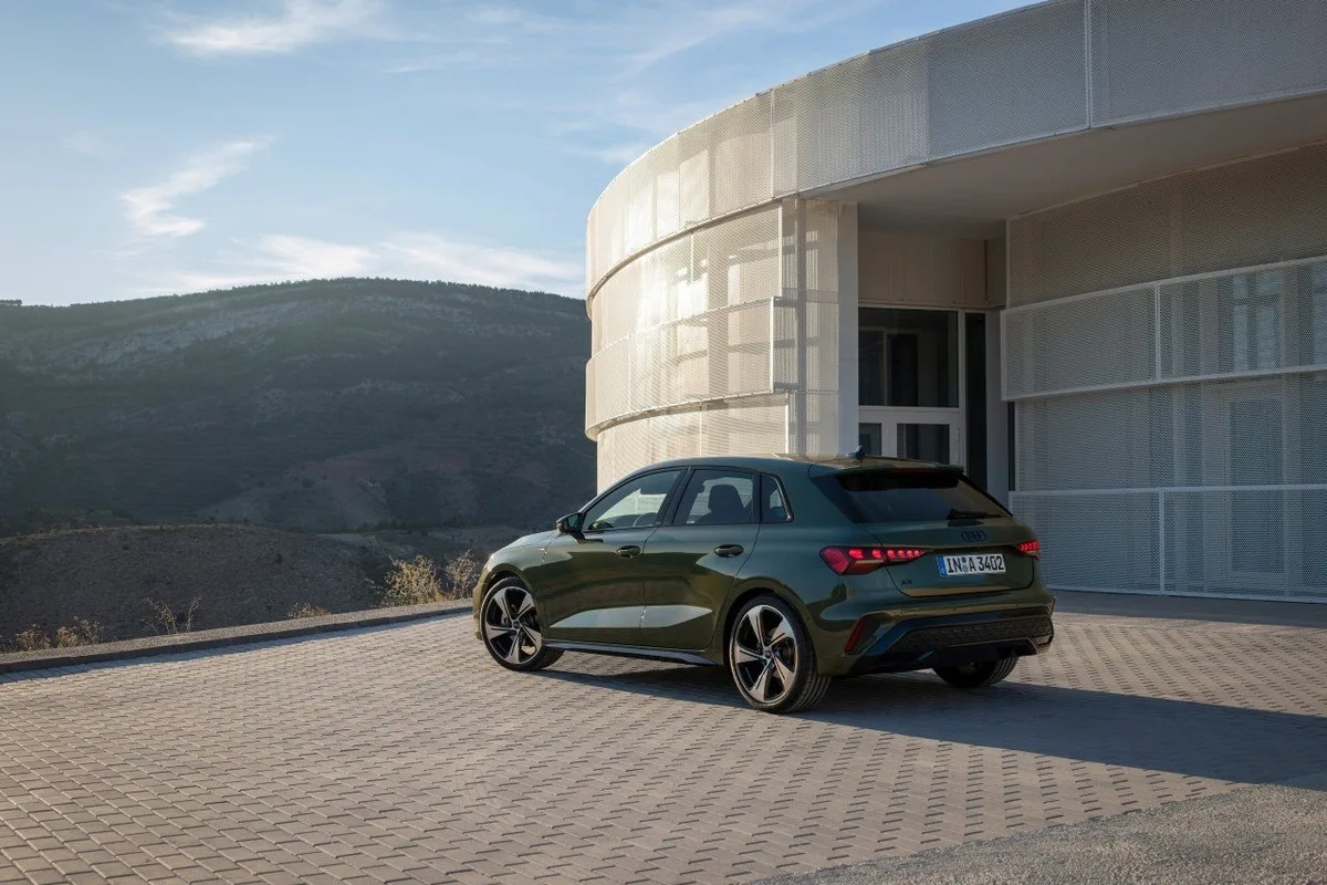 Green 2026 Audi A3 shown from the rear three-quarter angle beside a modern building.