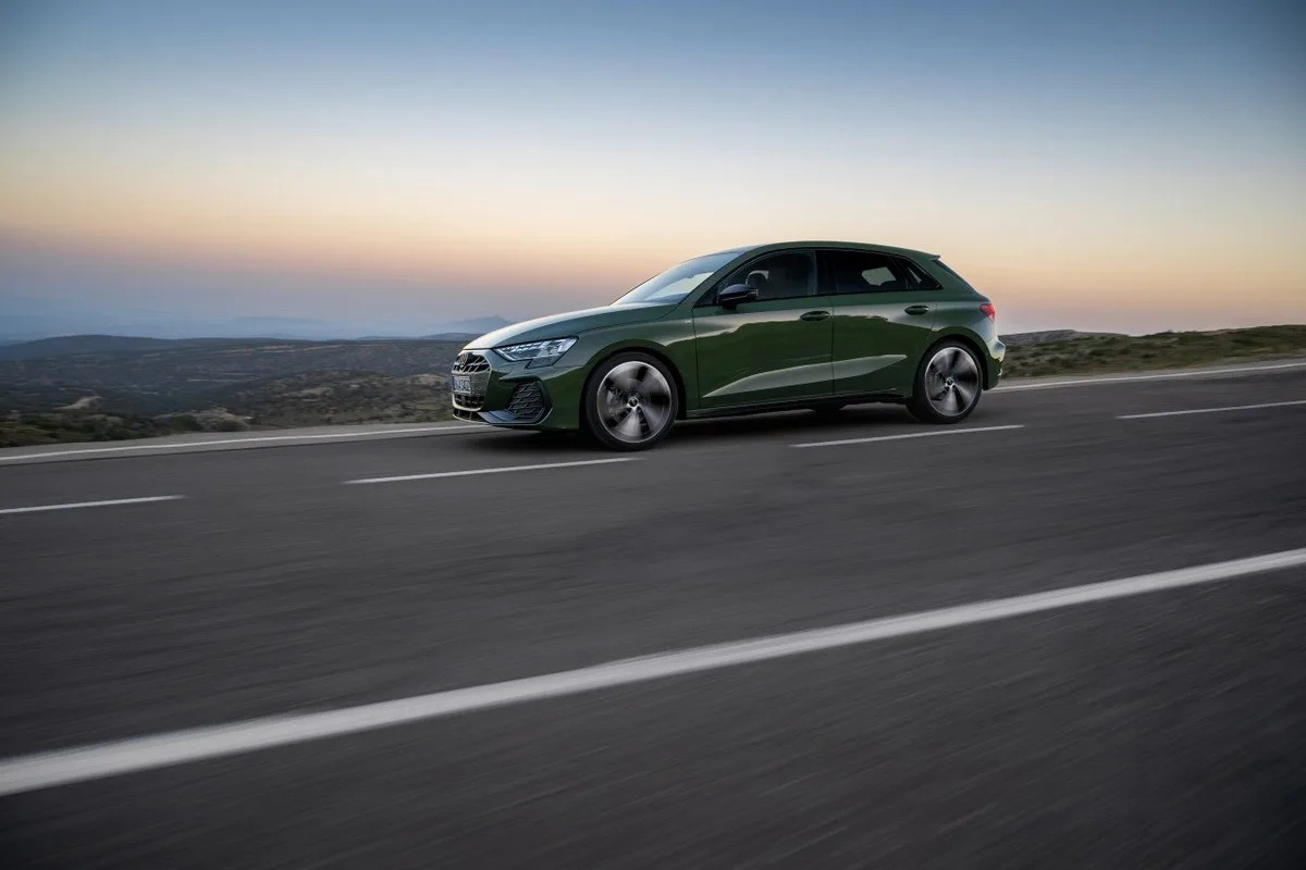 Green 2026 Audi A3 side profile driving on an open road at sunset.