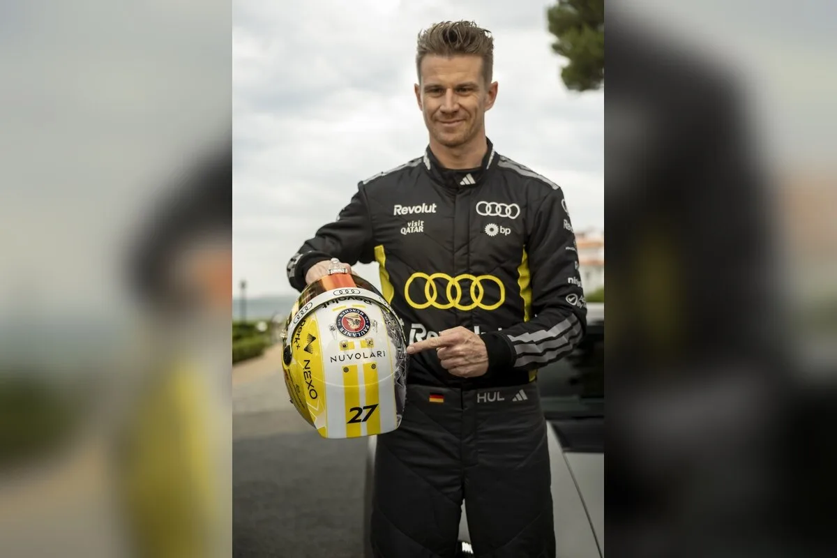 Nico Hulkenberg holding an Audi Nuvolari helmet beside the car