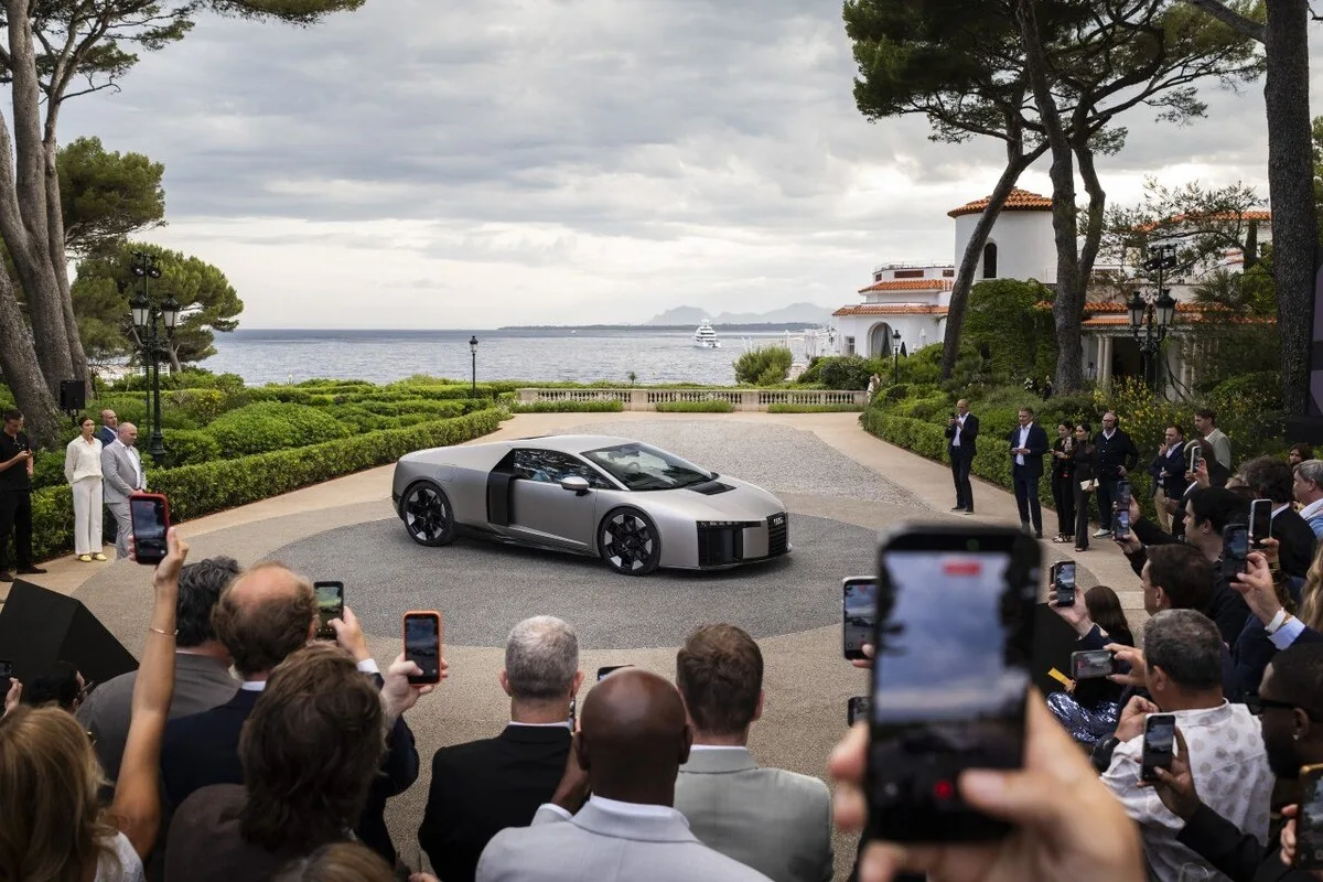Audi Nuvolari hypercar displayed at a coastal launch event with guests filming