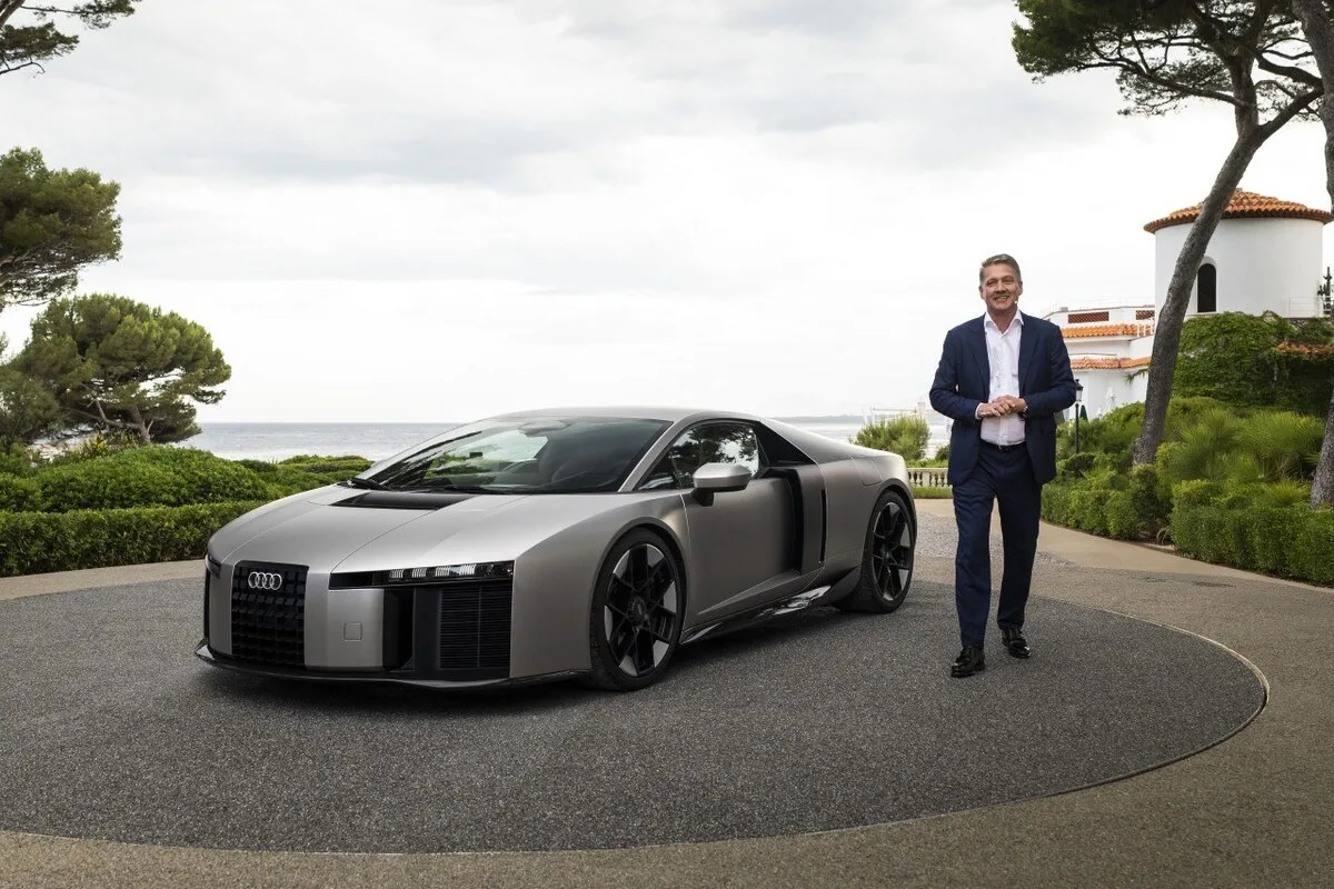 Audi Nuvolari hypercar with an Audi executive standing beside it at a coastal venue