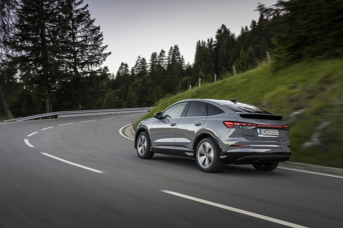 Audi Q4 e-tron Sportback seen from the rear on a winding forest road.