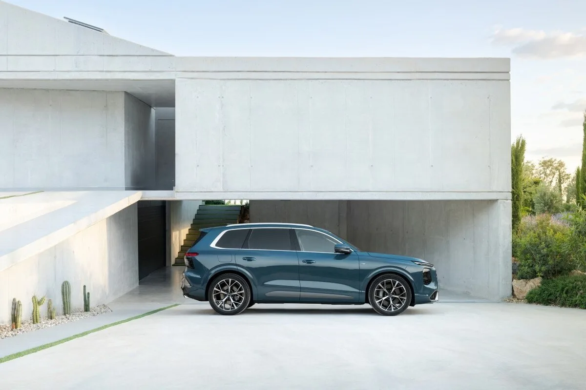 Audi Q7 side profile outside a modern concrete house