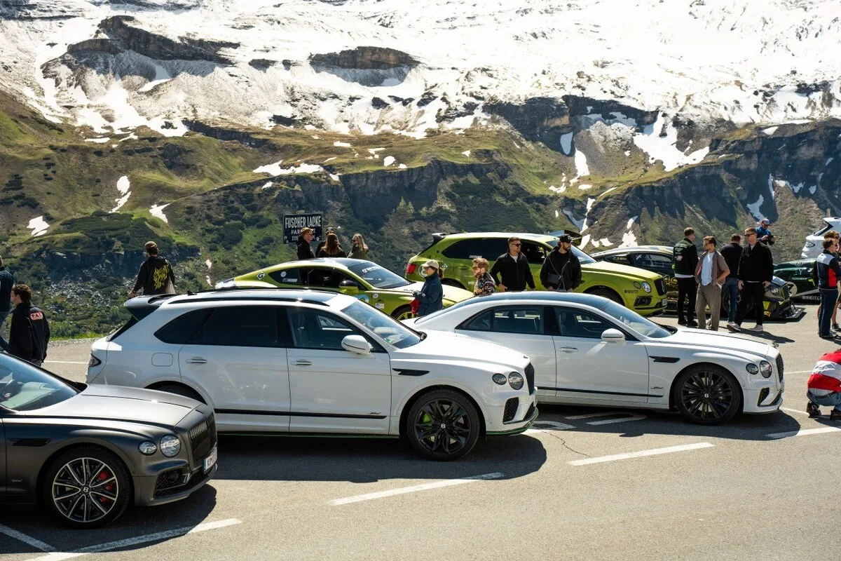 Bentley guests and cars gathered at FAT Mankei with snow-covered alpine peaks behind