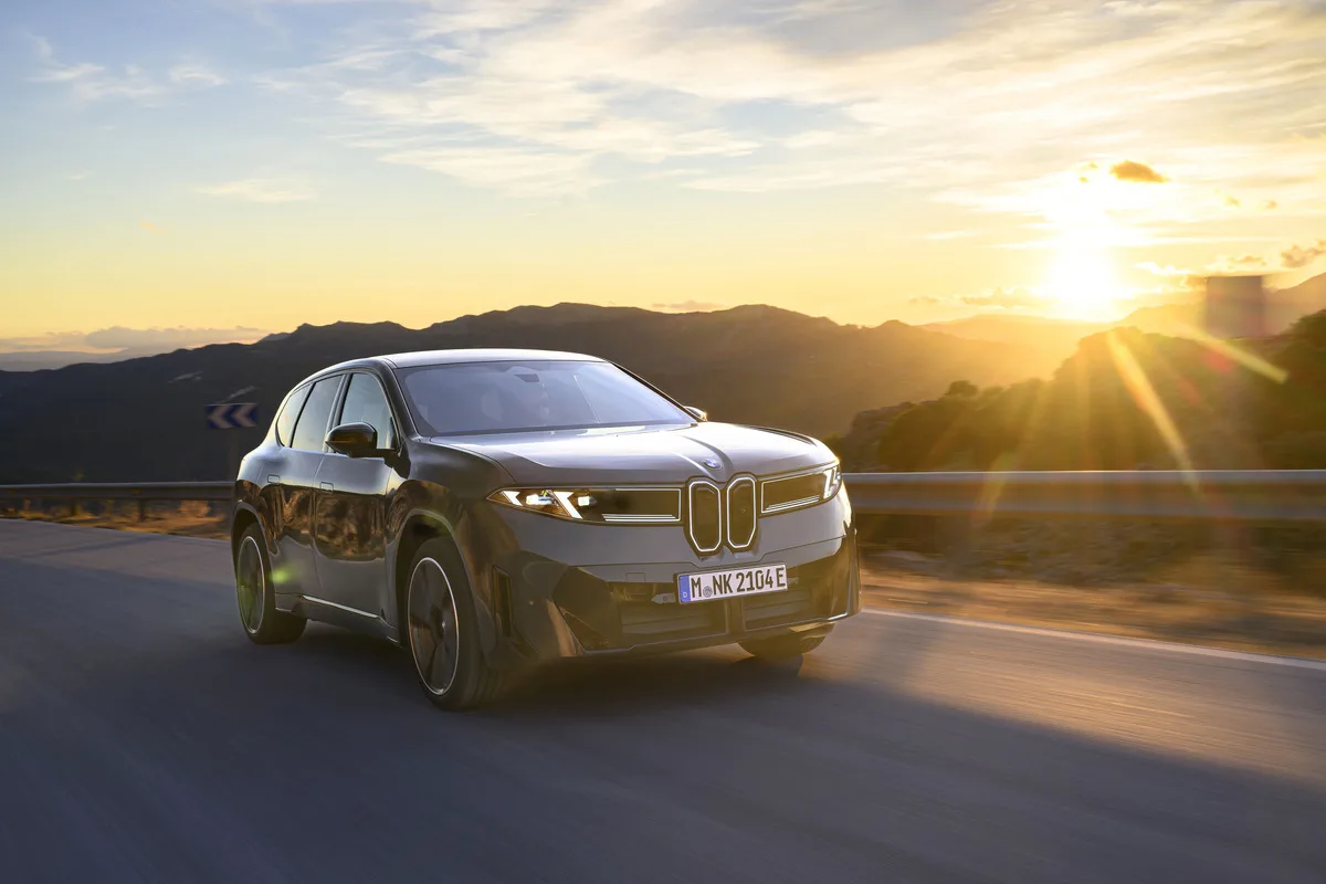 2026 BMW iX3 40 Neue Klasse electric SUV driving on a mountain road at sunset