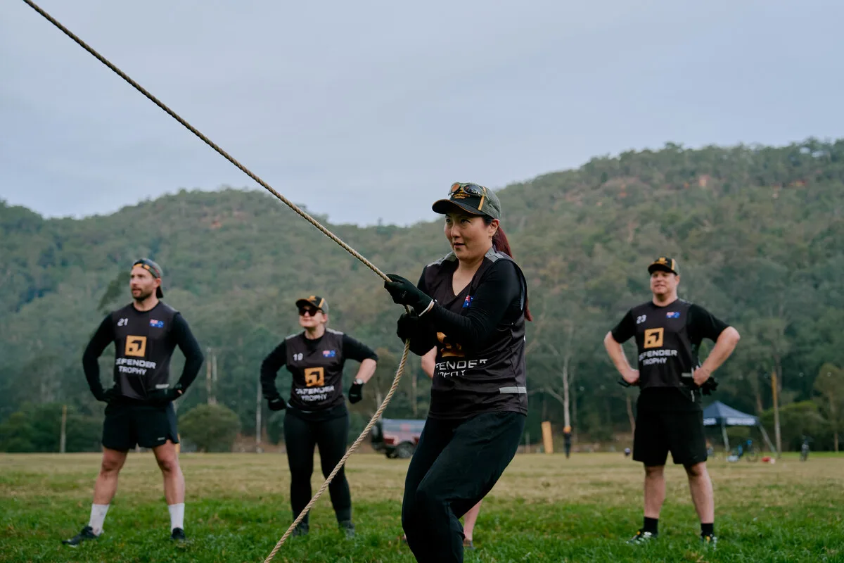 Defender Trophy competitors tackling an outdoor challenge with a Defender in the background