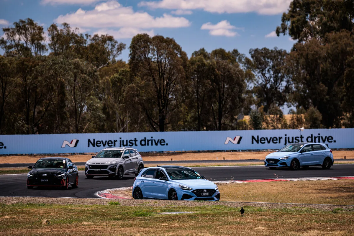 Four Hyundai N models driving past Never Just Drive circuit branding