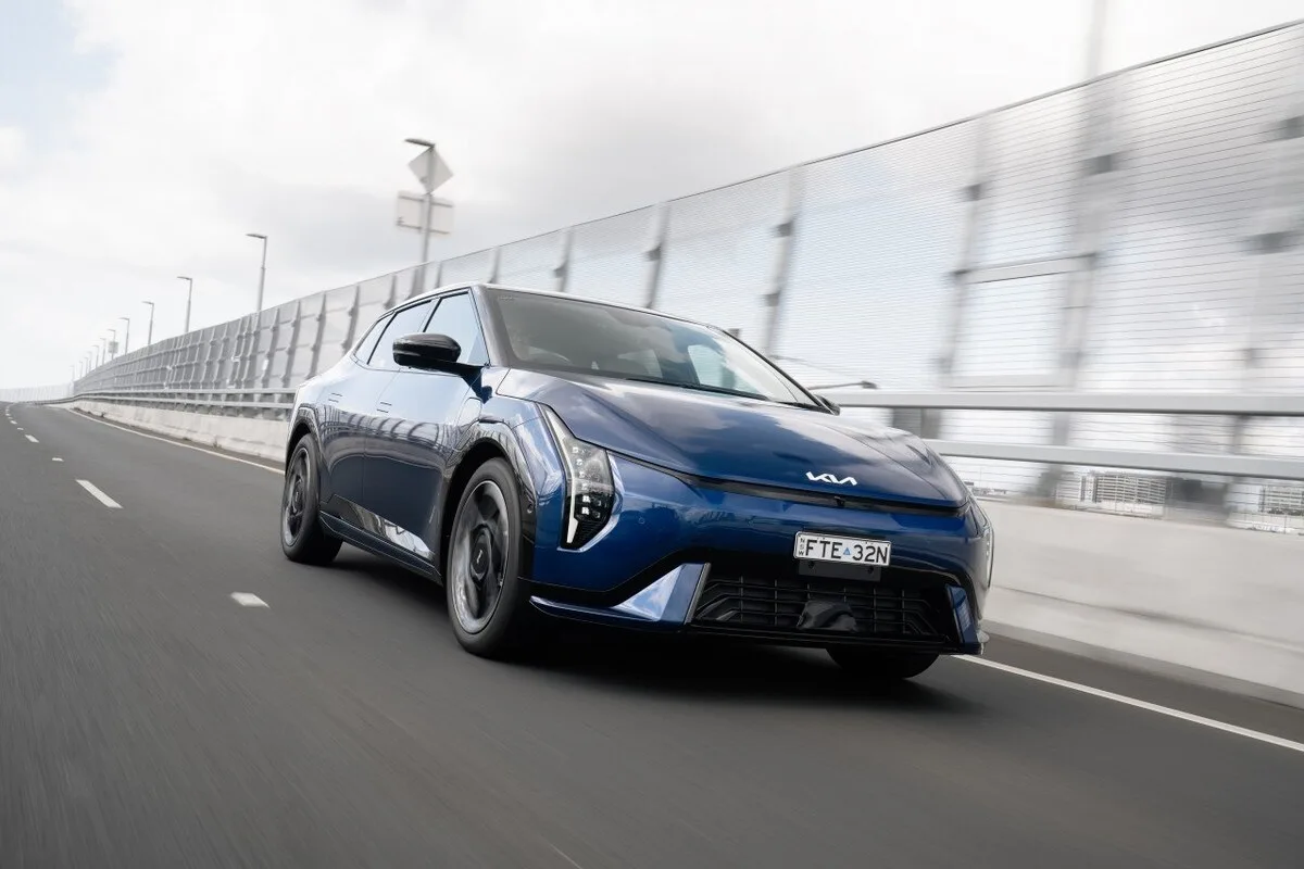Blue 2026 Kia EV4 Earth Long Range front three-quarter view driving on a city motorway