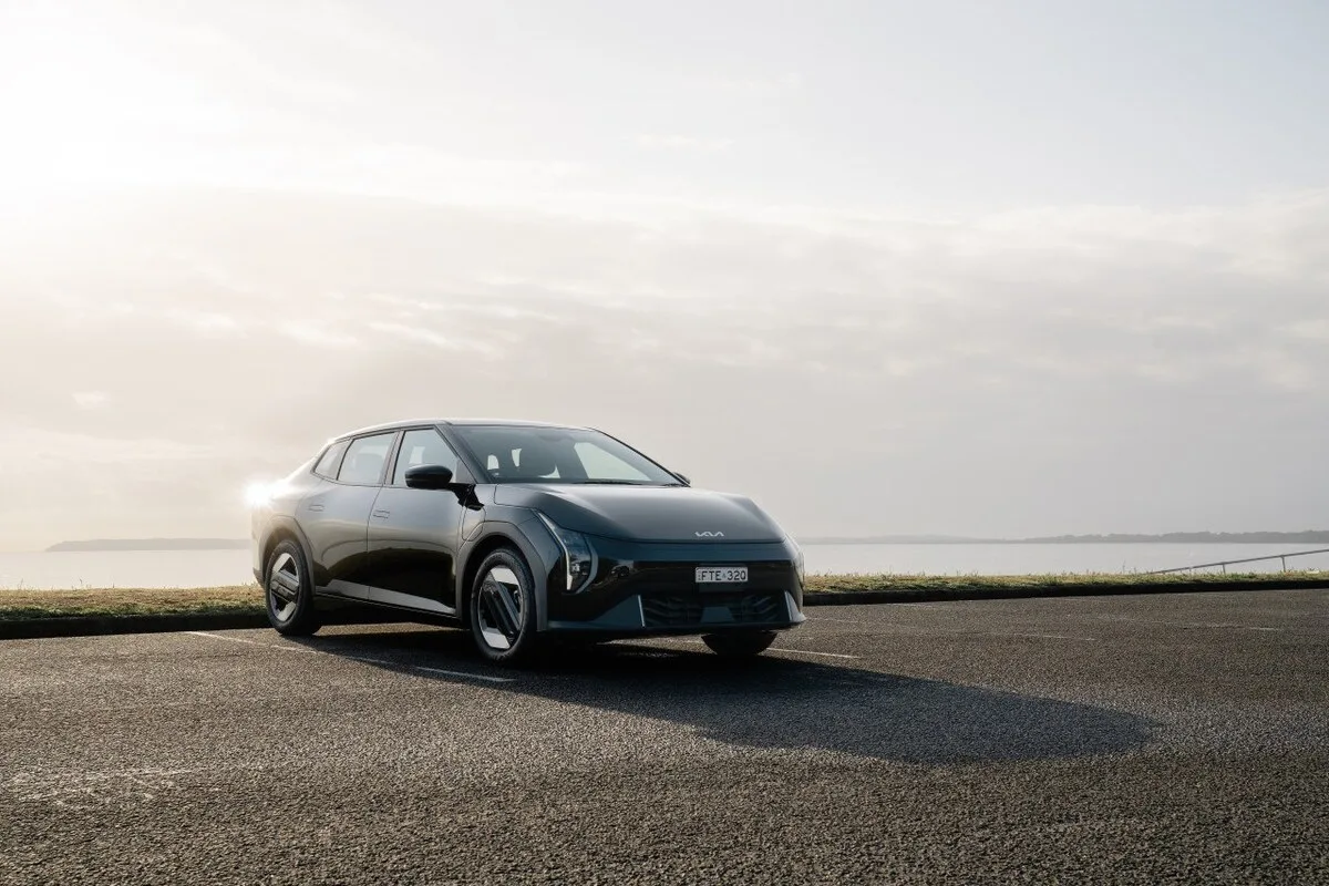 2026 Kia EV4 Earth Long Range front three-quarter view parked beside the coast at sunset
