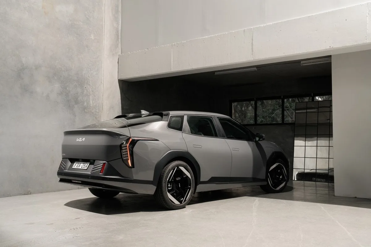 2026 Kia EV4 Earth Long Range rear three-quarter view parked beside a modern concrete building
