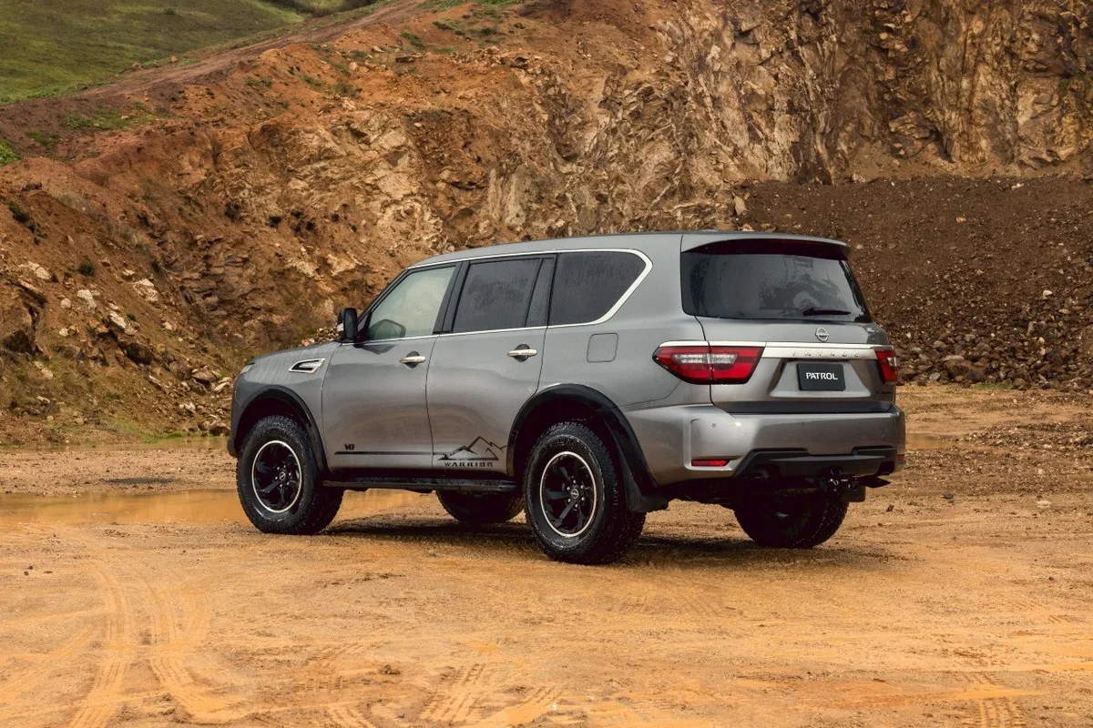 Grey Nissan Patrol Warrior shown from the rear three-quarter angle on rough ground.