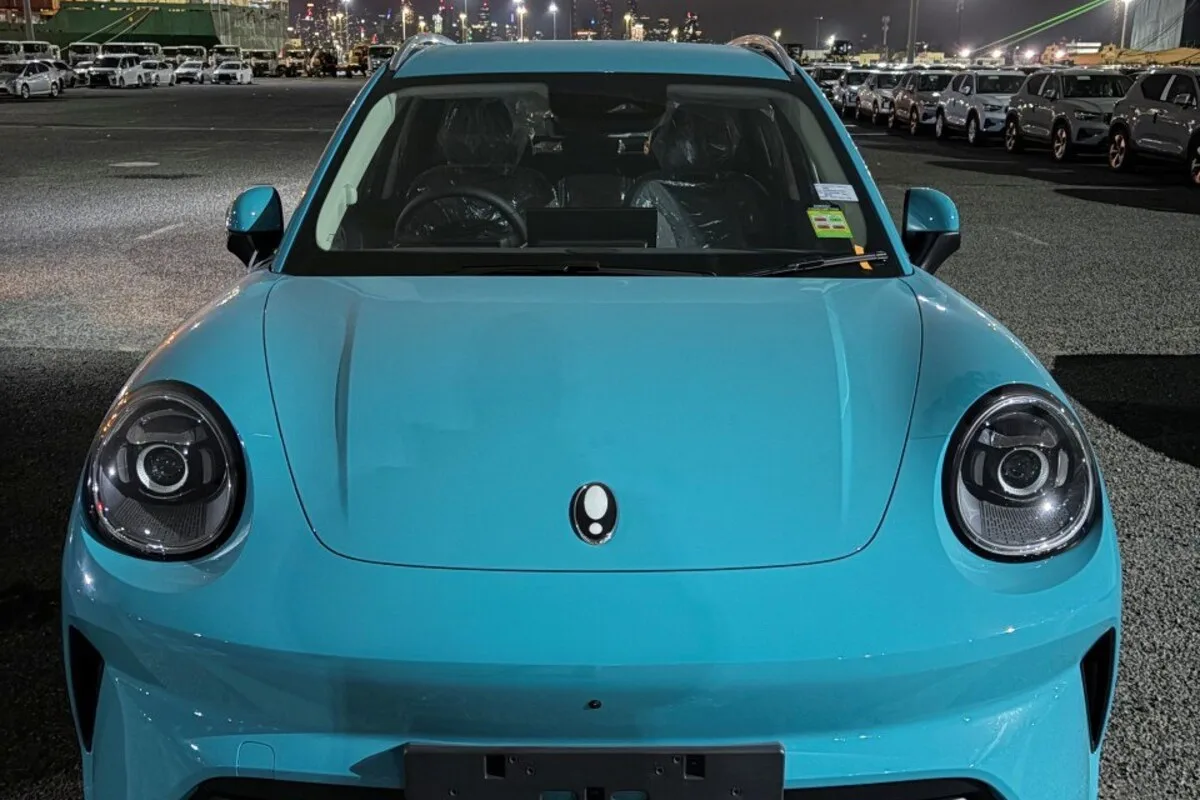 Front view of a turquoise ORA 5 SUV parked at an Australian port at night