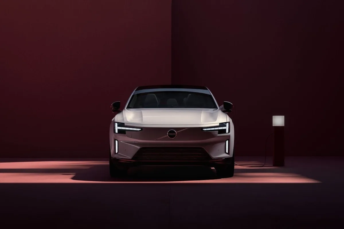 Volvo ES90 front view beside a charging point in a red studio setting
