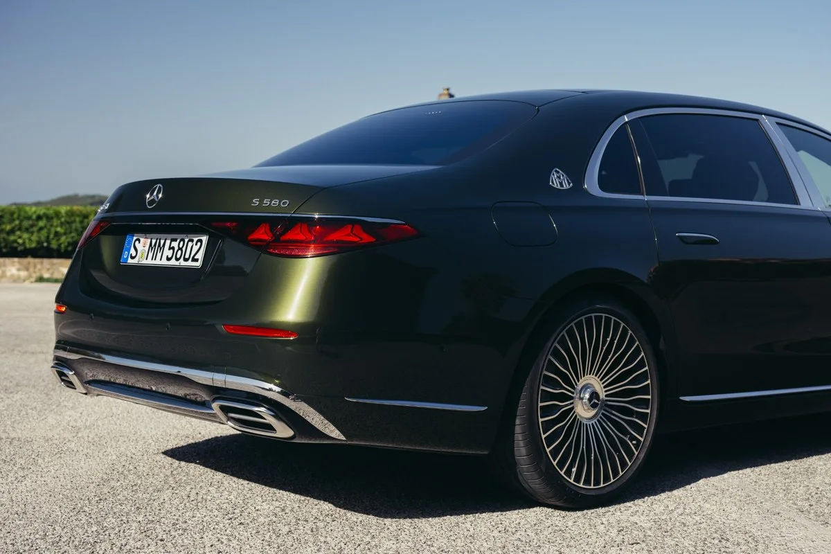 Rear detail of a dark green Mercedes-Maybach S 580 showing the badge, C-pillar emblem and multi-spoke forged wheel