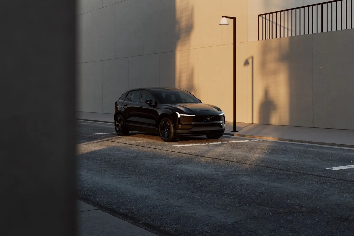 Black Volvo EX30 electric SUV parked on a city street beside a lamppost
