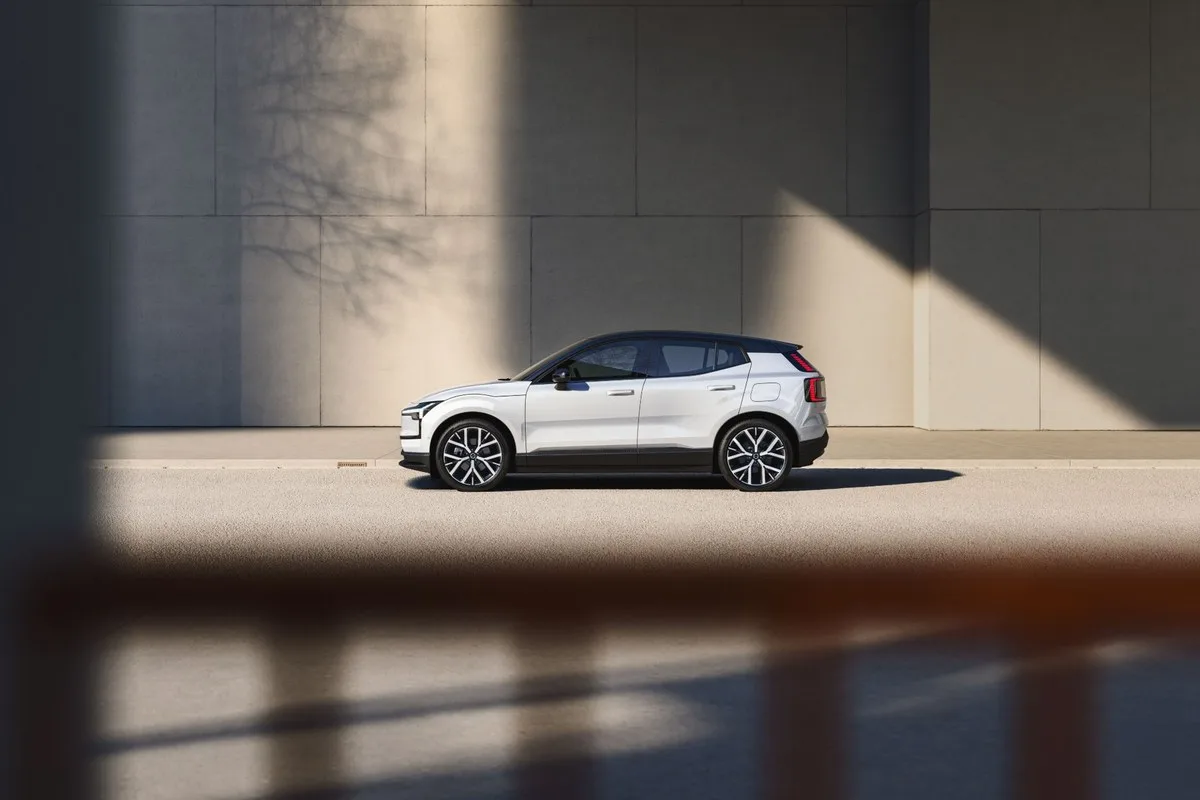 White Volvo EX30 electric SUV side profile against a concrete wall