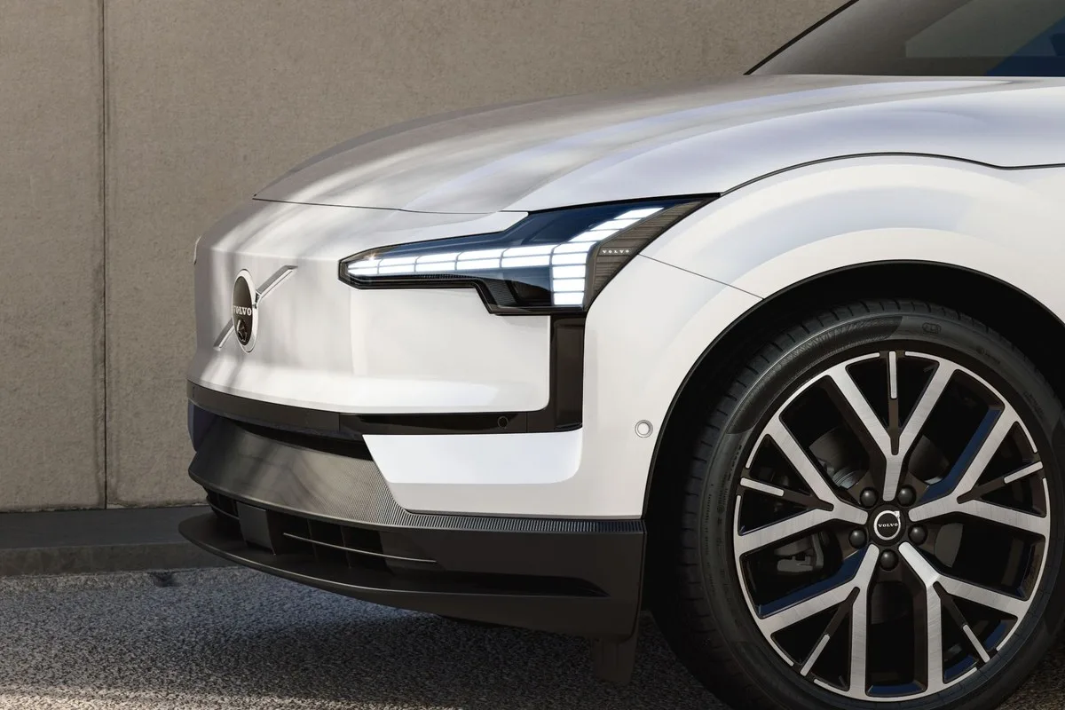 Front detail of the white Volvo EX30 showing the headlight, Volvo badge and alloy wheel