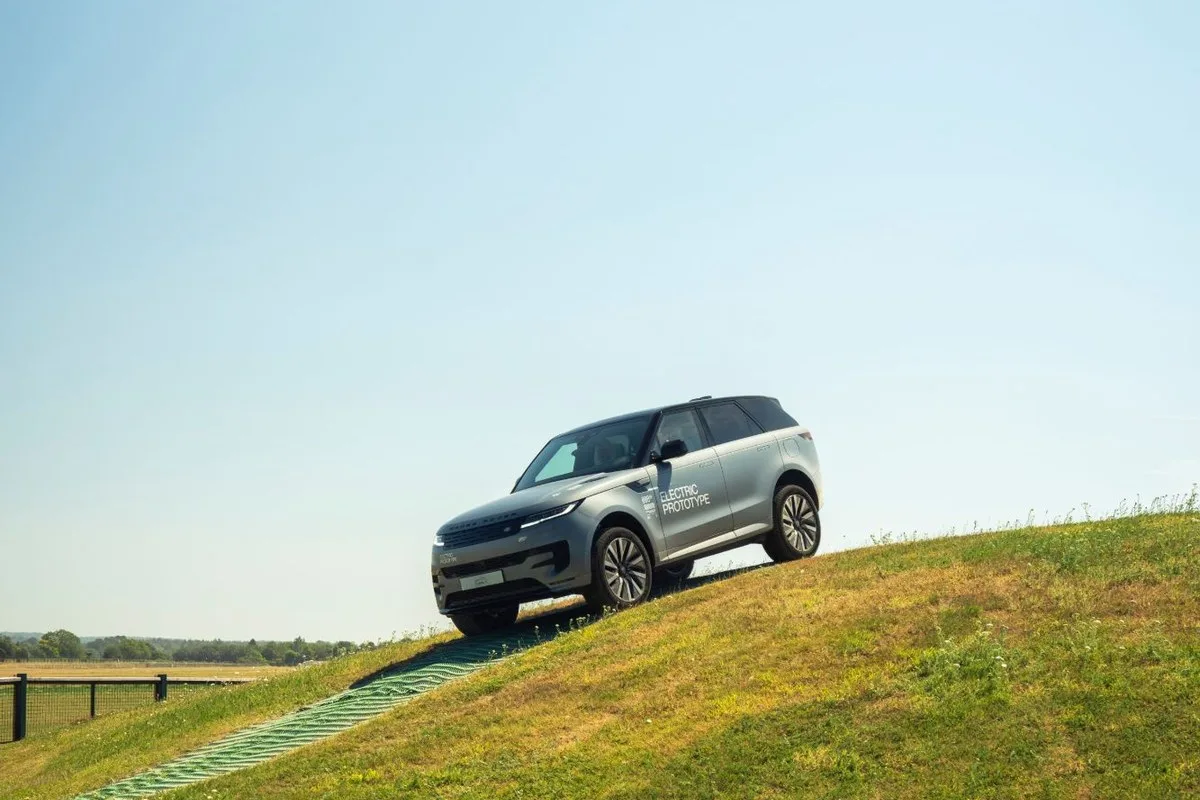 Silver Range Rover Sport Electric Prototype cresting a grassy off-road hill