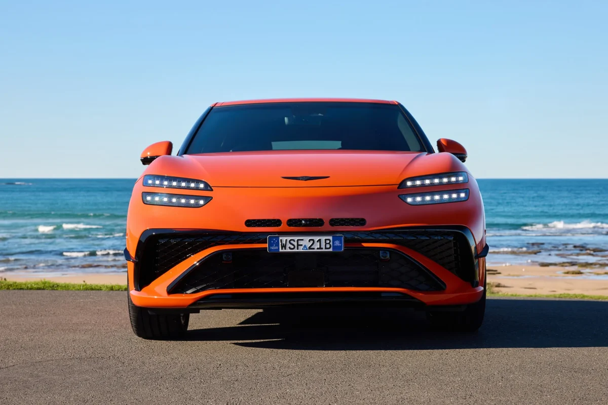 Magma Orange Genesis GV60 Magma front view parked on a coastal road by the sea