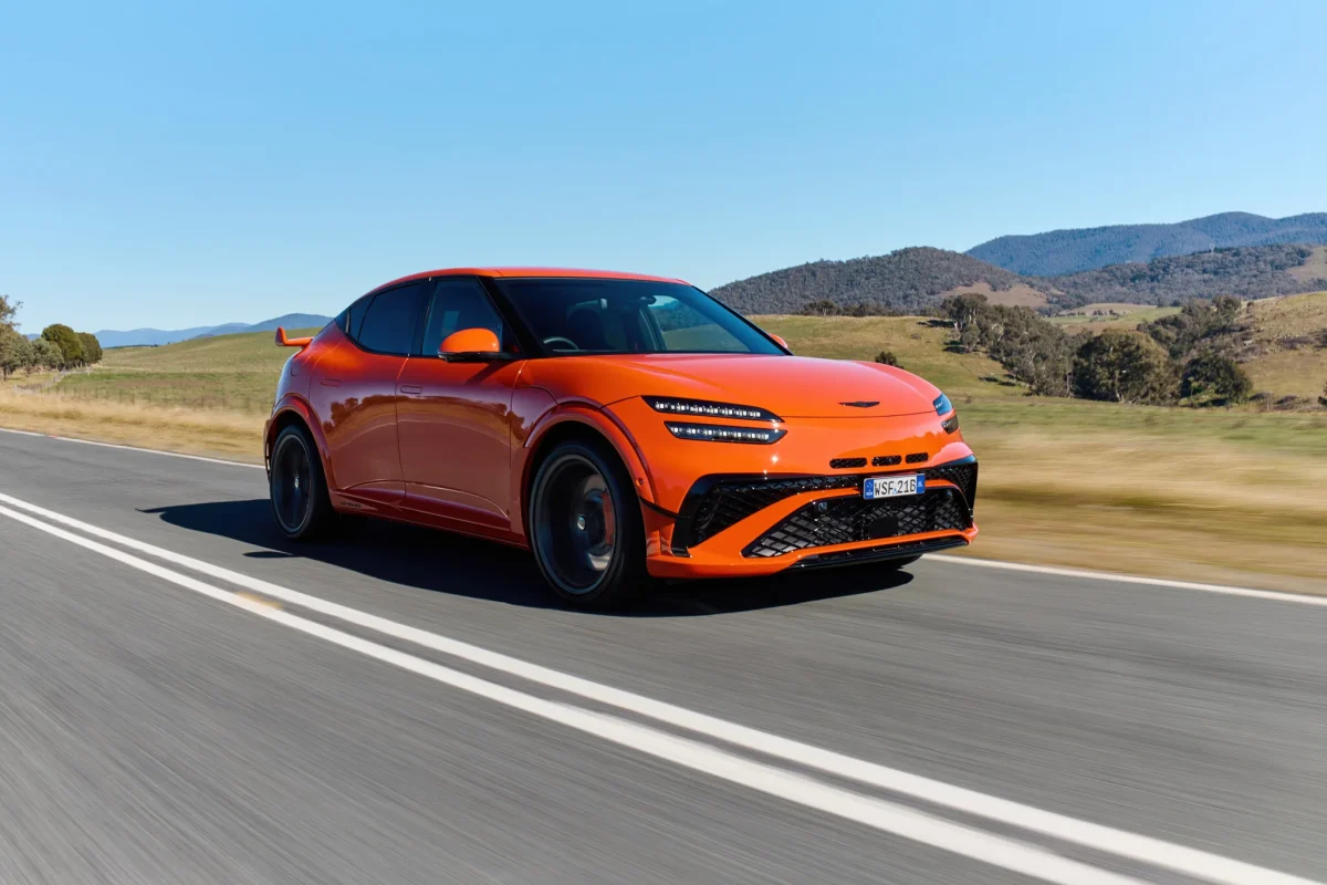 Magma Orange Genesis GV60 Magma driving on a country road, front three-quarter