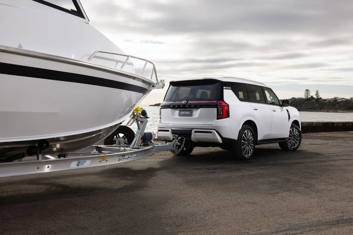 White 2027 Nissan Y63 Patrol hitched to a boat trailer at a boat ramp