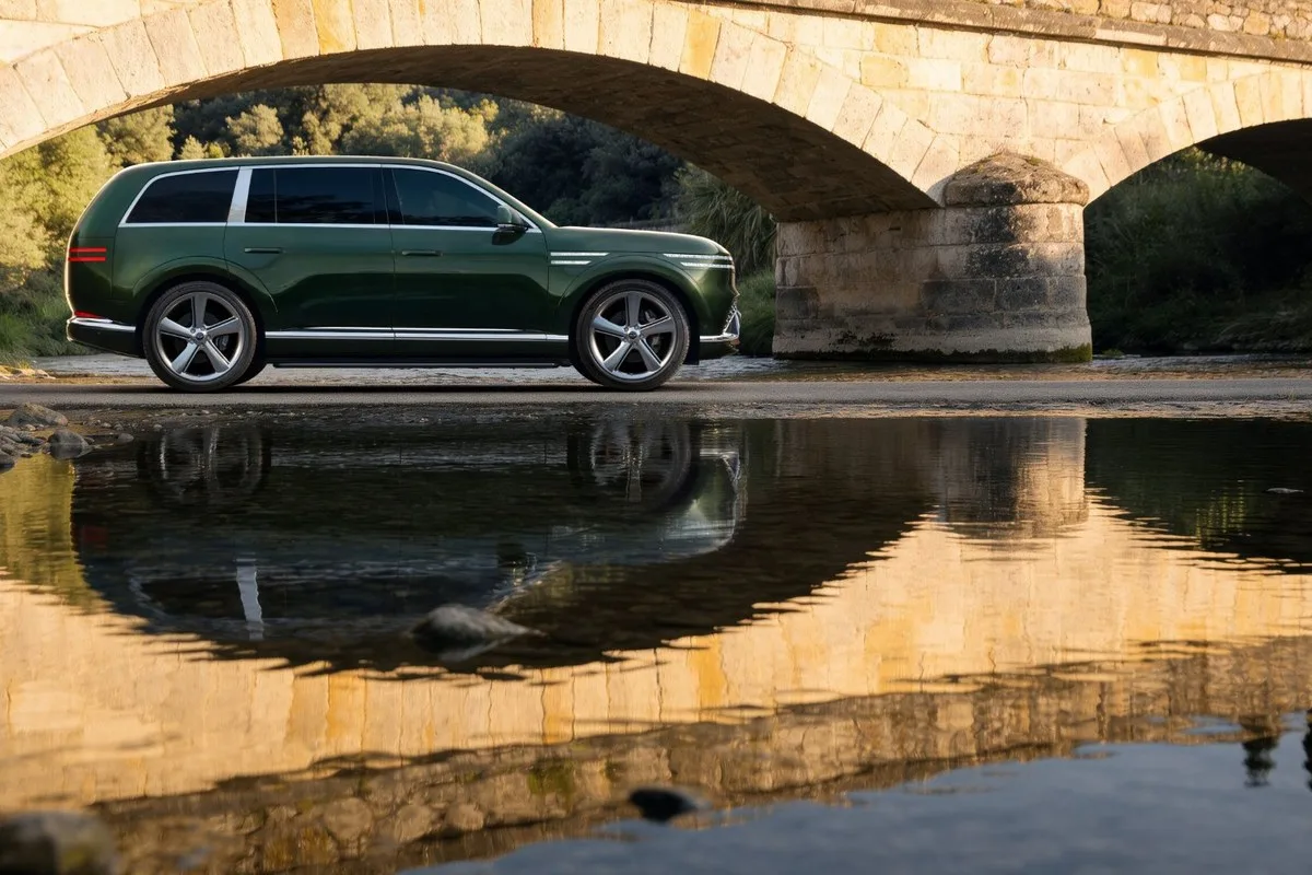 Green Genesis GV90 in side profile beside a stone bridge and water
