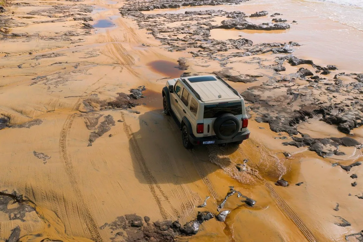Aerial view of a GWM Tank 300 Ultra Hi4-T crossing wet sand and rock shelf