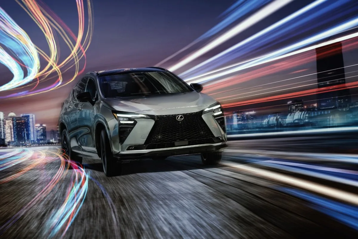 Silver 2027 Lexus NX driving at night with city light trails behind it