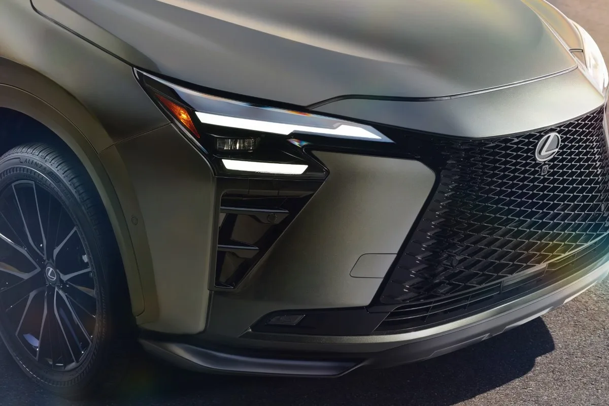 Close-up of the 2027 Lexus NX headlight, grille and front wheel in olive green