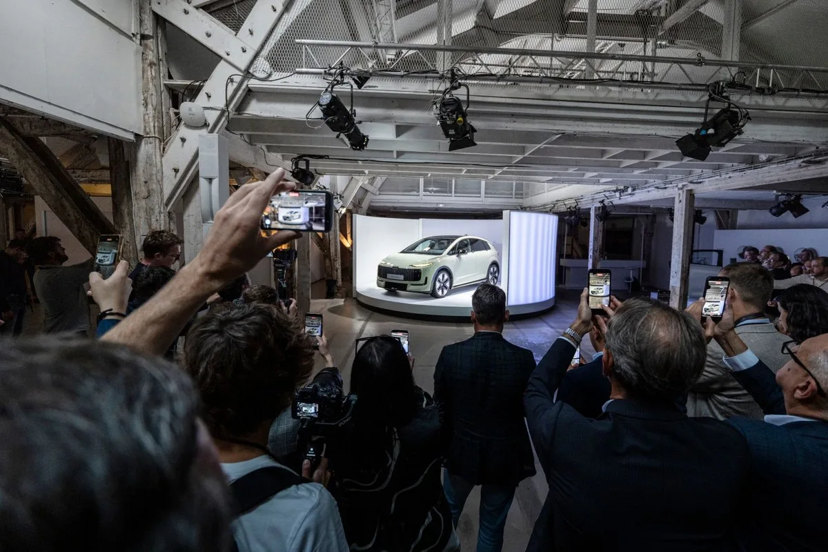 Press pack photographing the Audi A2 e-tron on a lit turntable at its Paris premiere