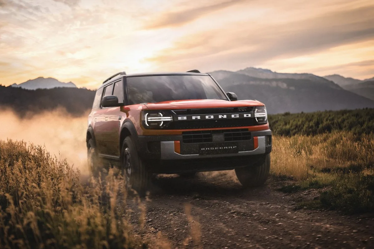Ford Bronco Basecamp in orange driving on a dirt track at sunset