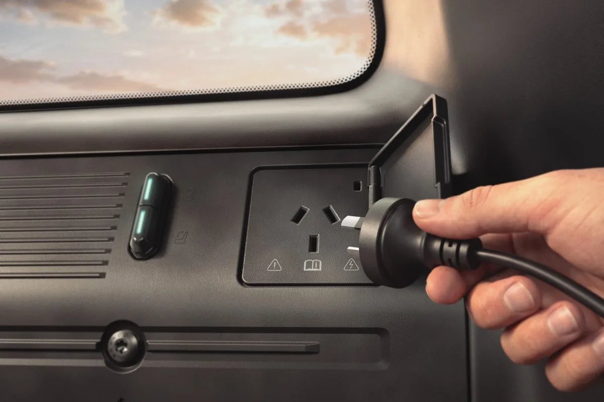 A hand plugging a three-pin plug into the Ford Bronco Basecamp power outlet in the boot