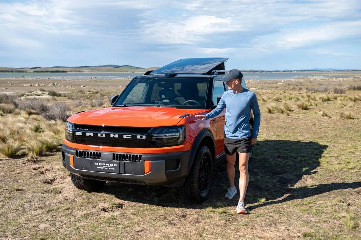 Orange Ford Bronco Basecamp prototype with its roof tent open, Nedd Brockmann standing beside it