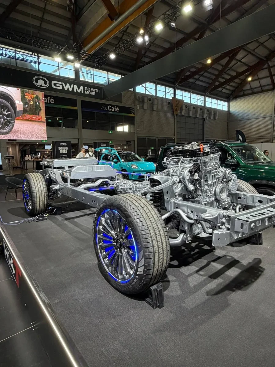 Bare GWM Hi4-T ladder-frame chassis on the GWM stand with engine, gearbox and battery pack exposed