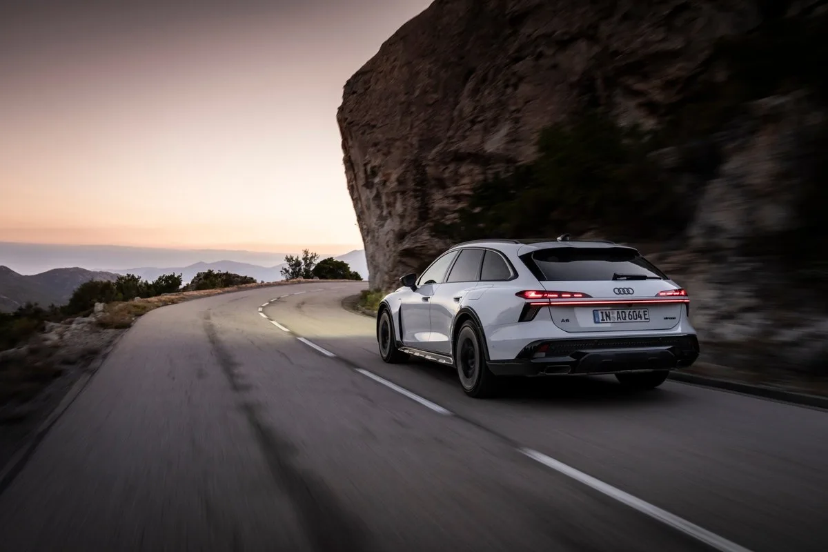 White Audi A6 allroad driving on a mountain road at dusk